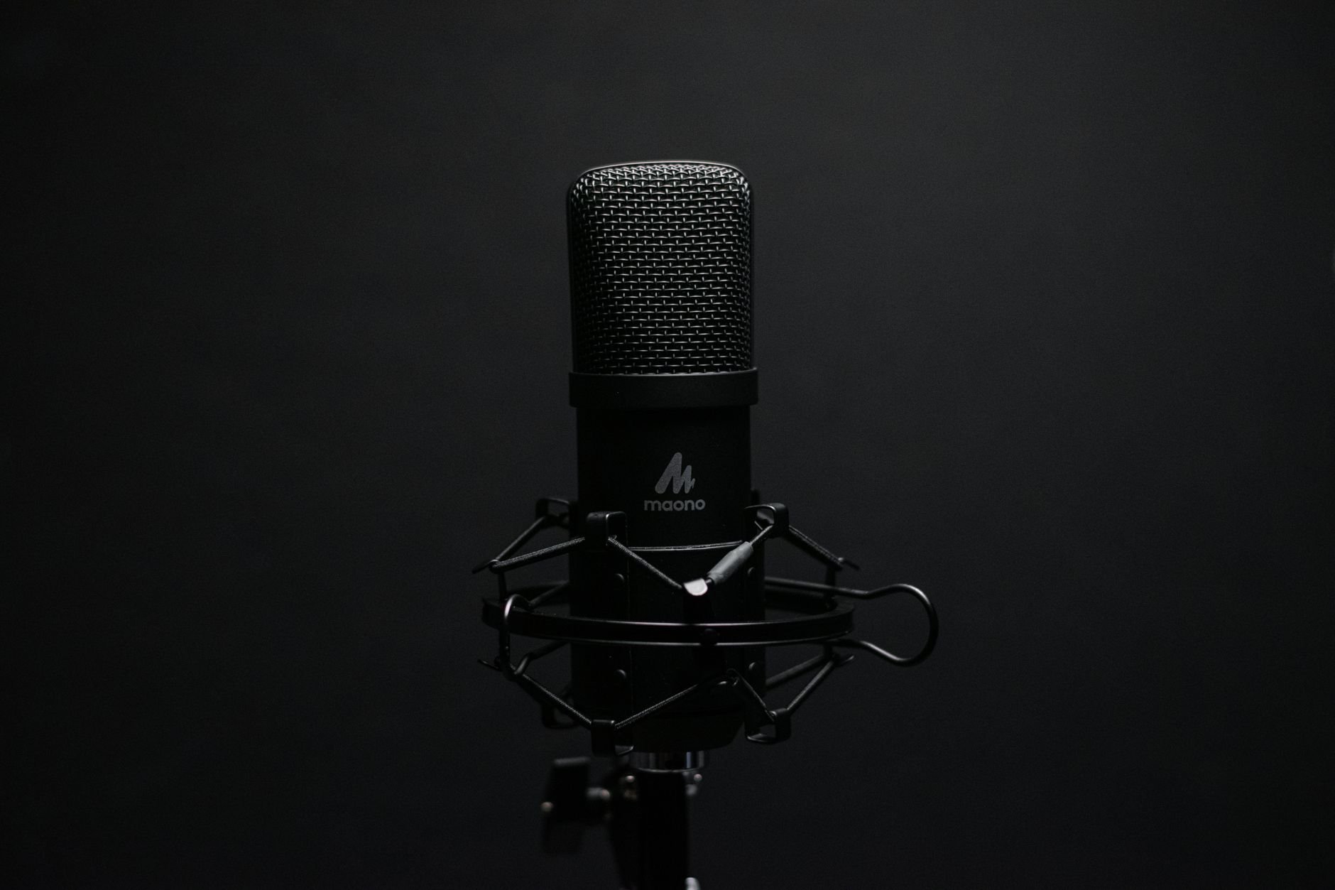 Studio microphone with shock mount on a dark backdrop, perfect for audio recording setups.